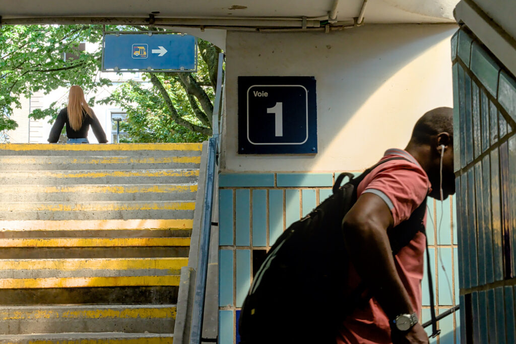 A man with a backpack walking up a flight of outdoor stairs in the city of Ath.