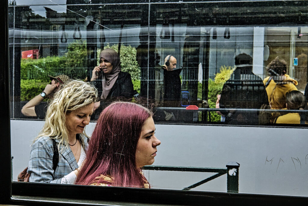 A blurred urban portrait of a person seen through a misted glass, surrounded by colorful reflections and city light.